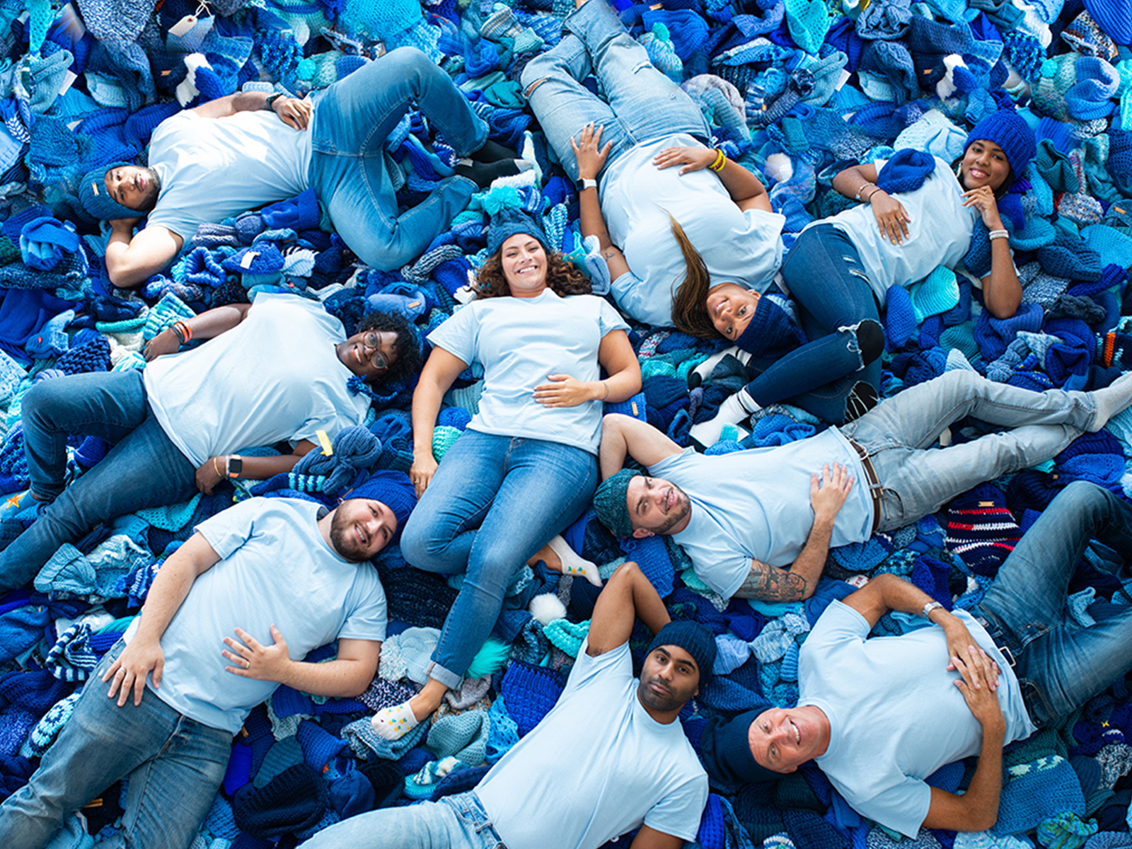 Shira and friends laying on pile of blue hats