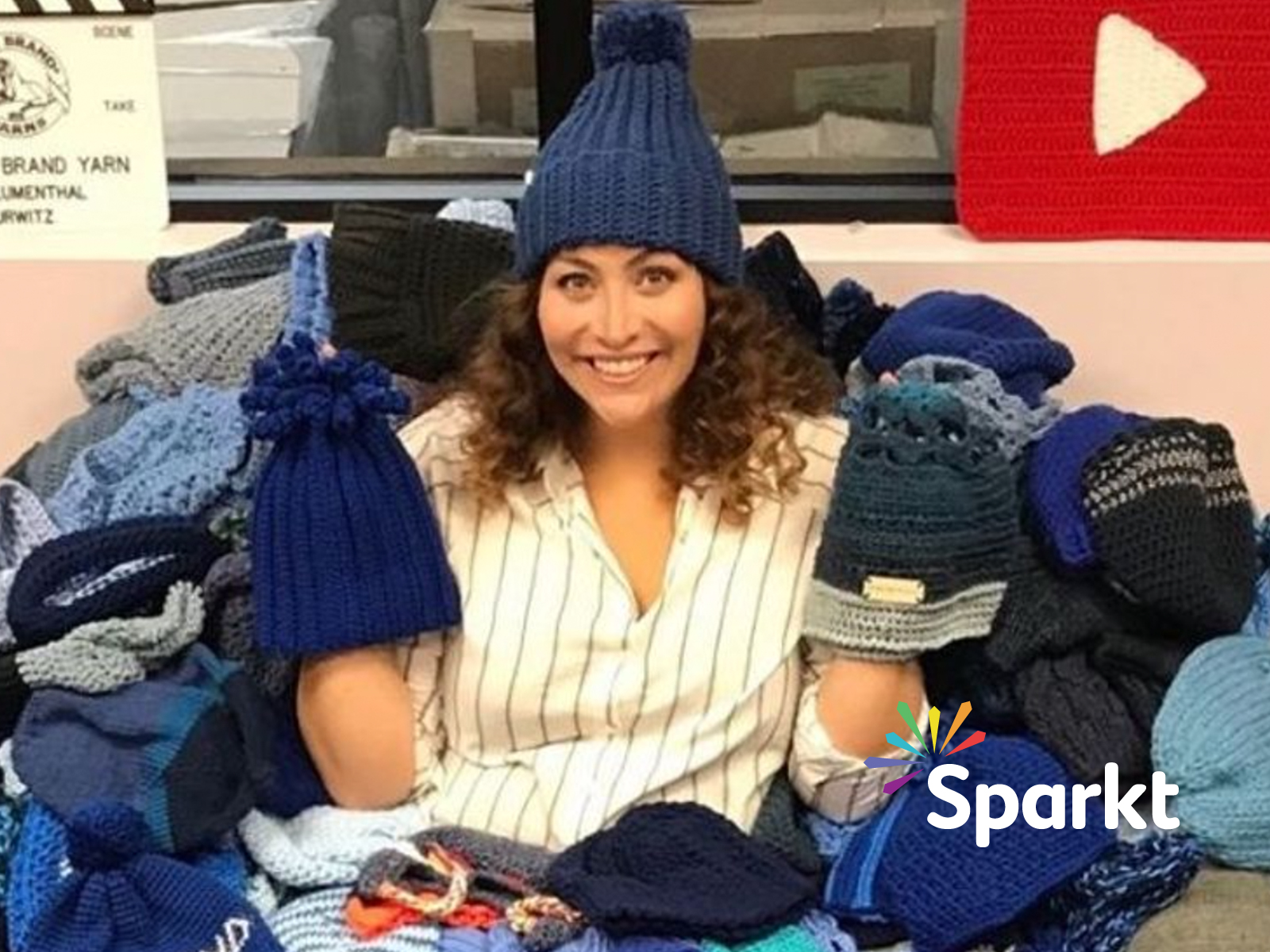 Sparkt logo overlaid on image of Shira with pile of hats